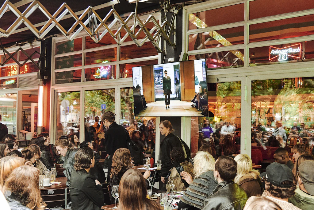 Dutzende Screens, die drinnen und draußen vor dem Diner montiert waren, verschmolzen Berlin und Mailand kurz zu einer Einheit.