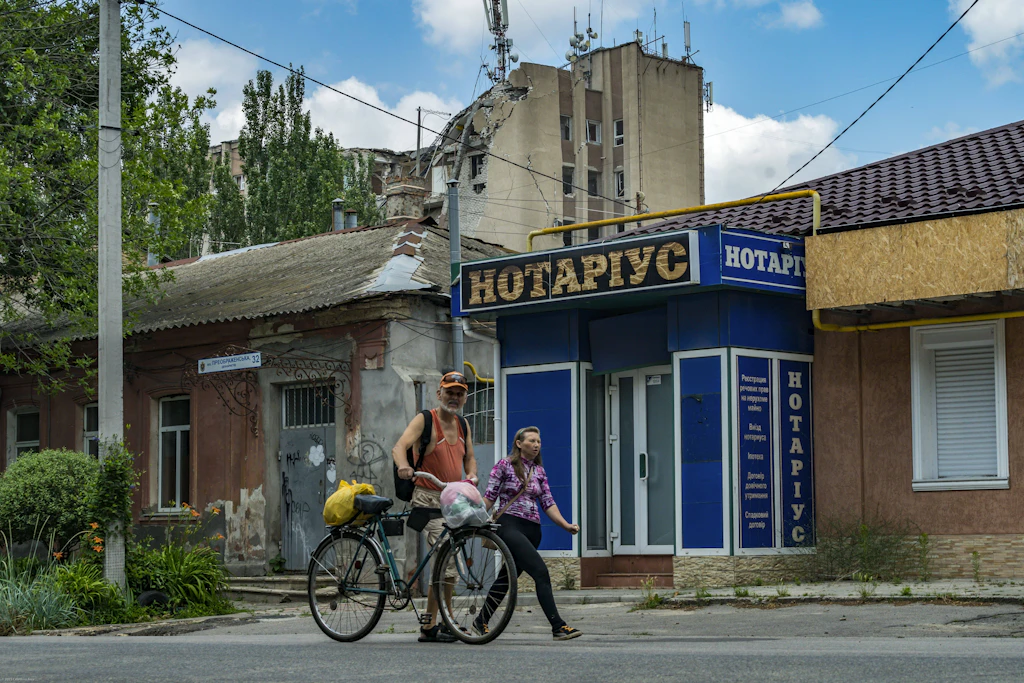 Bewohner von Cherson vor einem beschädigten Gebäude. Die Stadt liegt am Dnipro unweit der russisch besetzten Gebiete am gegenüberliegenden Ufer.