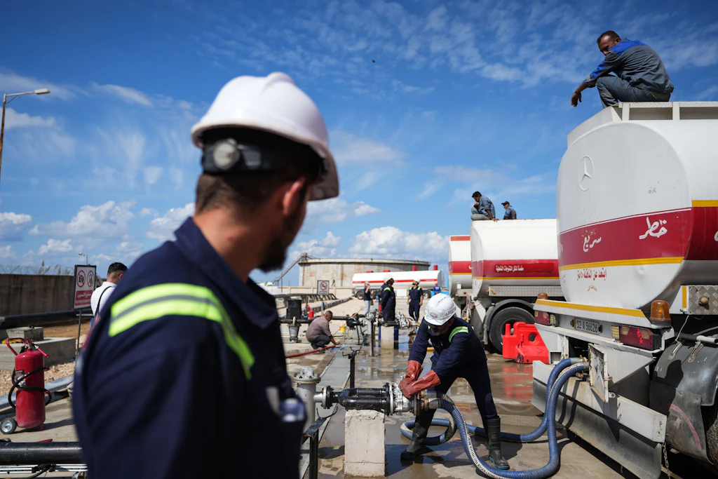 Arbeiter beladen am 27. September 2026 im syrischen Ölterminal Baniyas irakische Tanklastwagen mit Benzin.