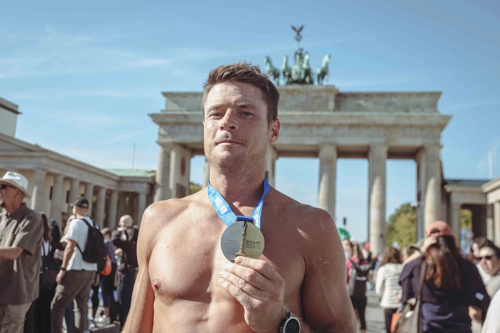 Krämpfe, eine halbe Stunde über der Bestzeit, aber die Medaille in der Hand: Jared aus Kanada nach seinem ersten Berlin-Marathon vor dem Brandenburger Tor.