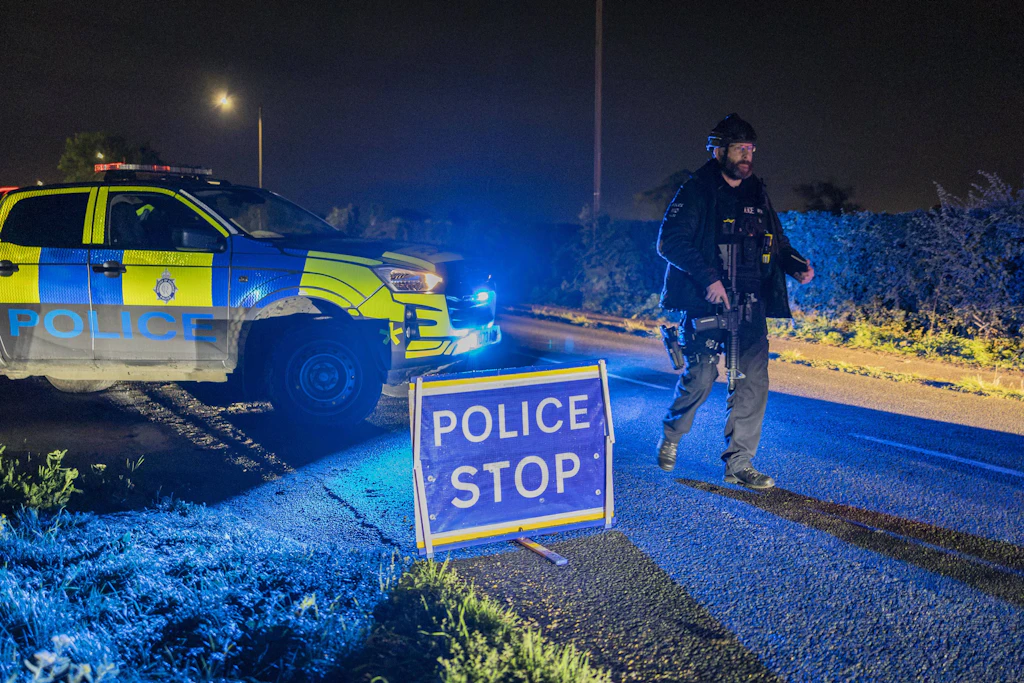 Bewaffnete Polizisten sichern Zufahrten zur RAF Fairford. Fünf Männer wurden nach einem Terrorverdacht nahe dem Luftwaffenstützpunkt festgenommen.