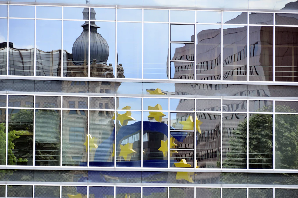 Die blaue Euroskulptur mit gelben Sternen spiegelt sich in Glasfenstern am Eurotower in Frankfurt am Main – ein Symbol für Deutschlands Finanzplatz.