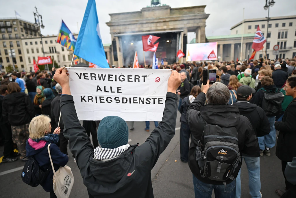 Protest vor dem Brandenburger Tor: Ein Demonstrant hält ein Transparent mit der Aufschrift „Verweigert alle Kriegsdienste“ hoch.