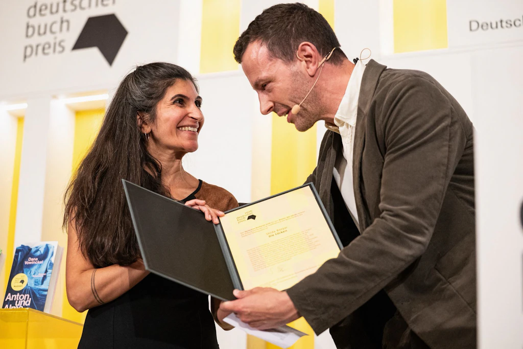 Shida Bazyar bekommt die Urkunde von Sebastian Guggolz, Vorsteher des Börsenvereins des Deutschen Buchhandels, überreicht.