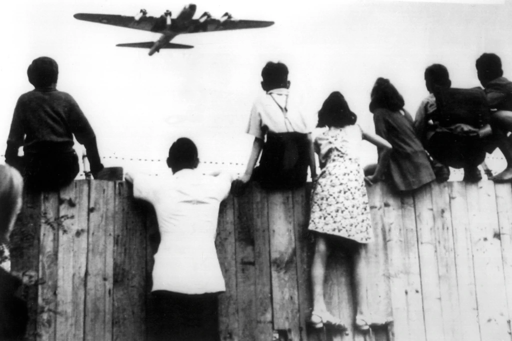 Kinder beobachten 1948 die Landung eines US-Flugzeugs am Flughafen Tempelhof. Die Luftbrücke wurde zum Symbol des amerikanischen Schutzversprechens für West-Berlin.