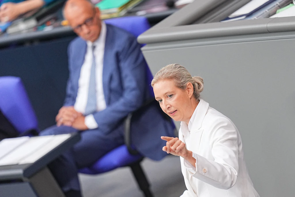 AfD-Chefin Alice Weidel spricht im Bundestag, Bundeskanzler Friedrich Merz (CDU) sitzt hinter ihr.