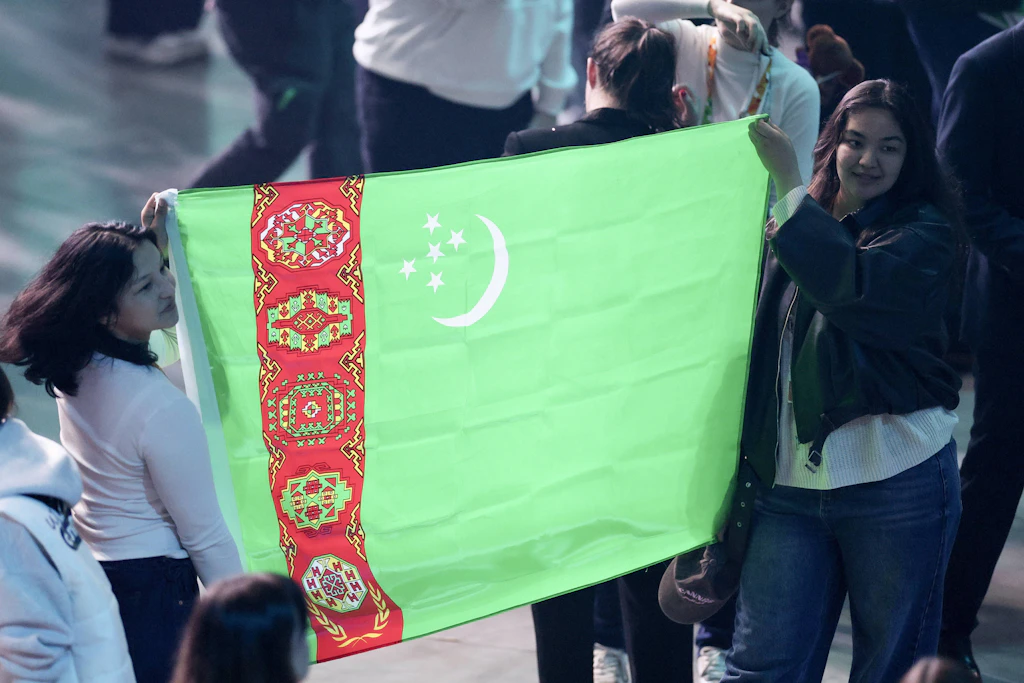 Junge Turkmeninnen halten die Landesflagge bei einem Kongress hoch. Ihr Land will sich für Touristen und Geschäftsreisende öffnen.