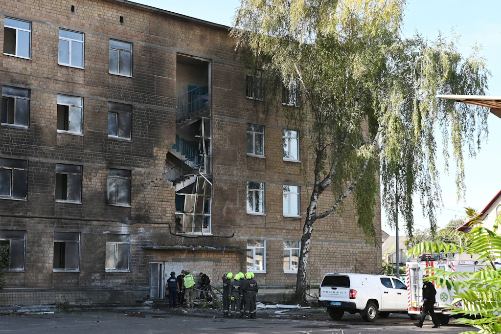 Polizisten und Einsatzkräfte stehen am 1. Oktober vor einem durch einen russischen Drohnenangriff beschädigten Schulgebäude in Kiew.