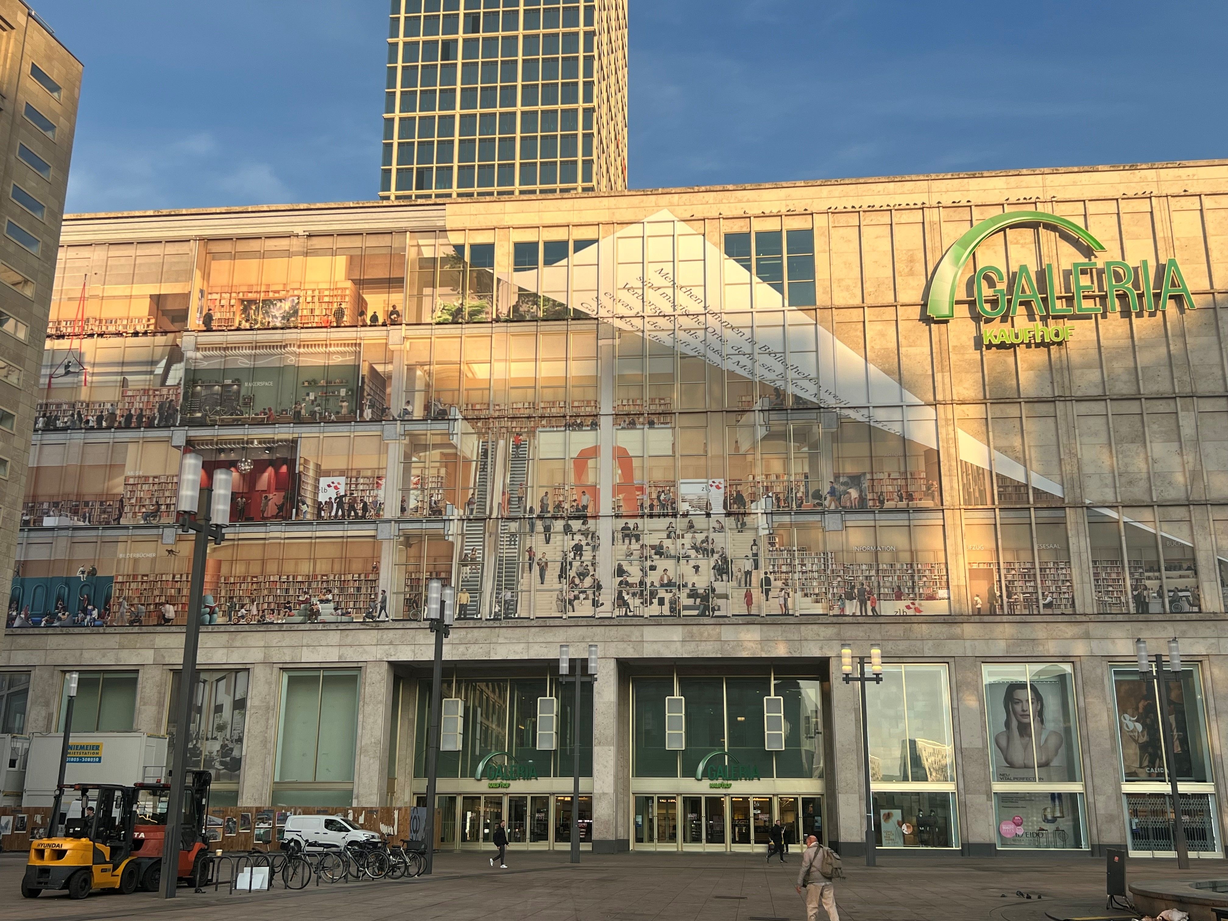 Wer steckt hinter dem Riesen-Plakat am Alexanderplatz: Es zeigt Galeria als Mega-Bibliothek
