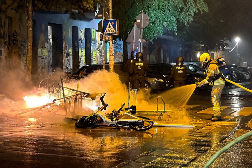Unter Polizeischutz löscht die Feuerwehr eine brennende Barrikade in der Rigaer Straße.