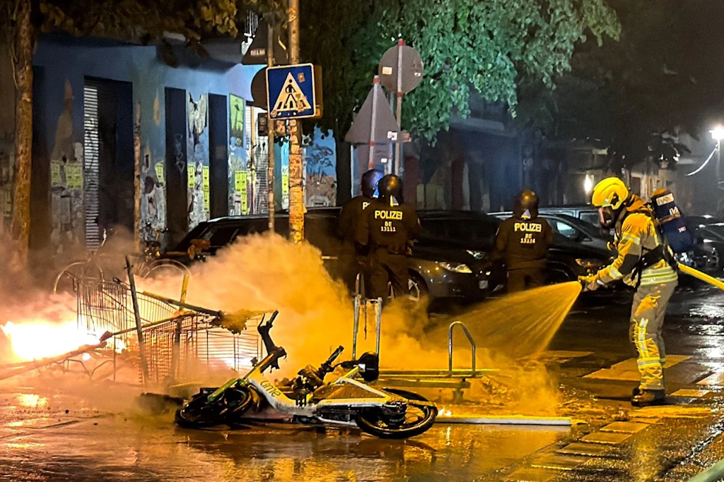 Unter Polizeischutz löscht die Feuerwehr eine brennende Barrikade in der Rigaer Straße.