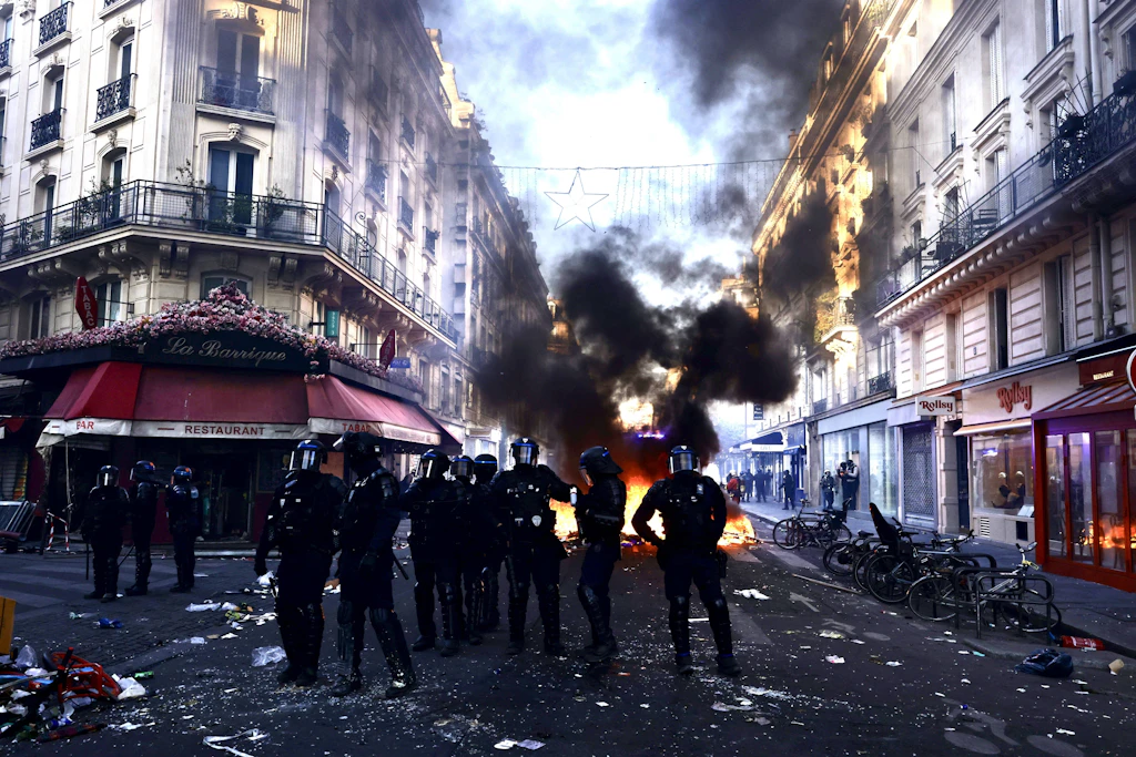 Polizisten vor einer brennenden Barrikade in Paris. Für manche Beobachter führt die Spur des Feuers direkt nach Moskau.