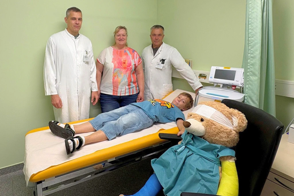 Nach der ersten roboterassistierten Operation eines Kindes an der Uniklinik Magdeburg stehen Ärzte, Mutter und der Junge bei der Nachsorge zusammen.