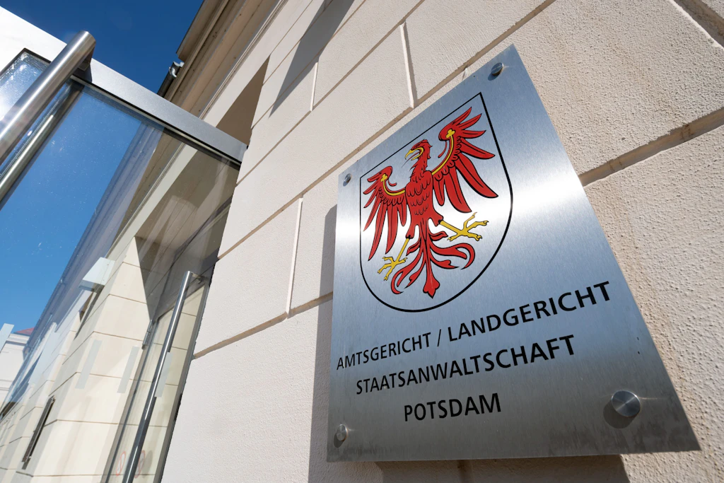 Das Metallschild neben dem Eingang zum Justizzentrum mit dem roten Adler als Landeswappen und dem Verweis auf Amtsgericht, Landgericht und Staatsanwaltschaft.