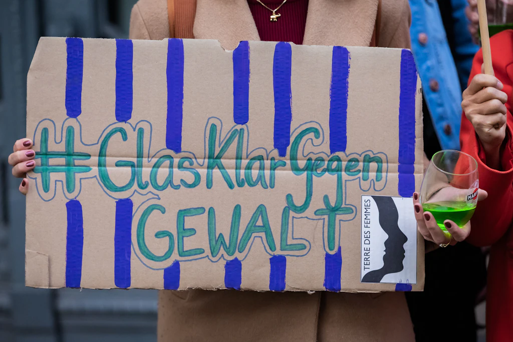 Eine Frau protestiert mit einem Glas  mit grüner Flüssigkeit vor dem Kriminalgericht Moabit.